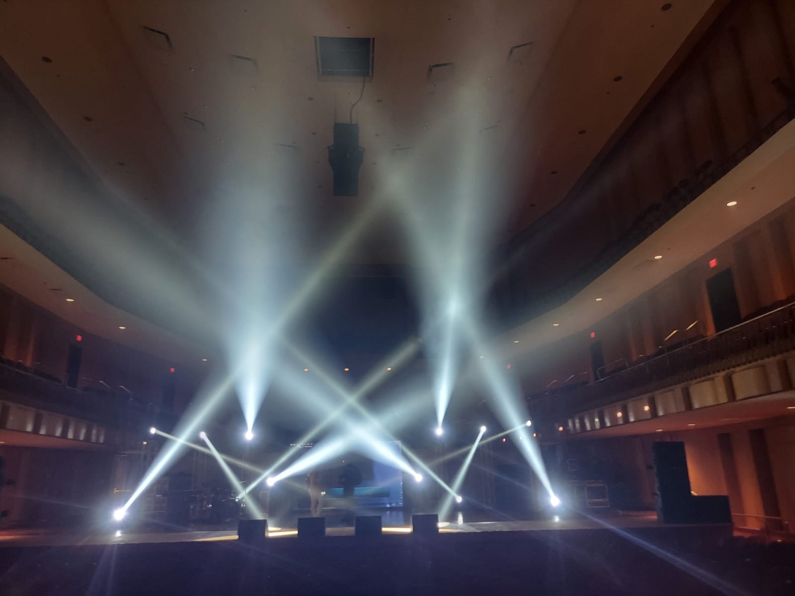 White beams cross above a theater stage