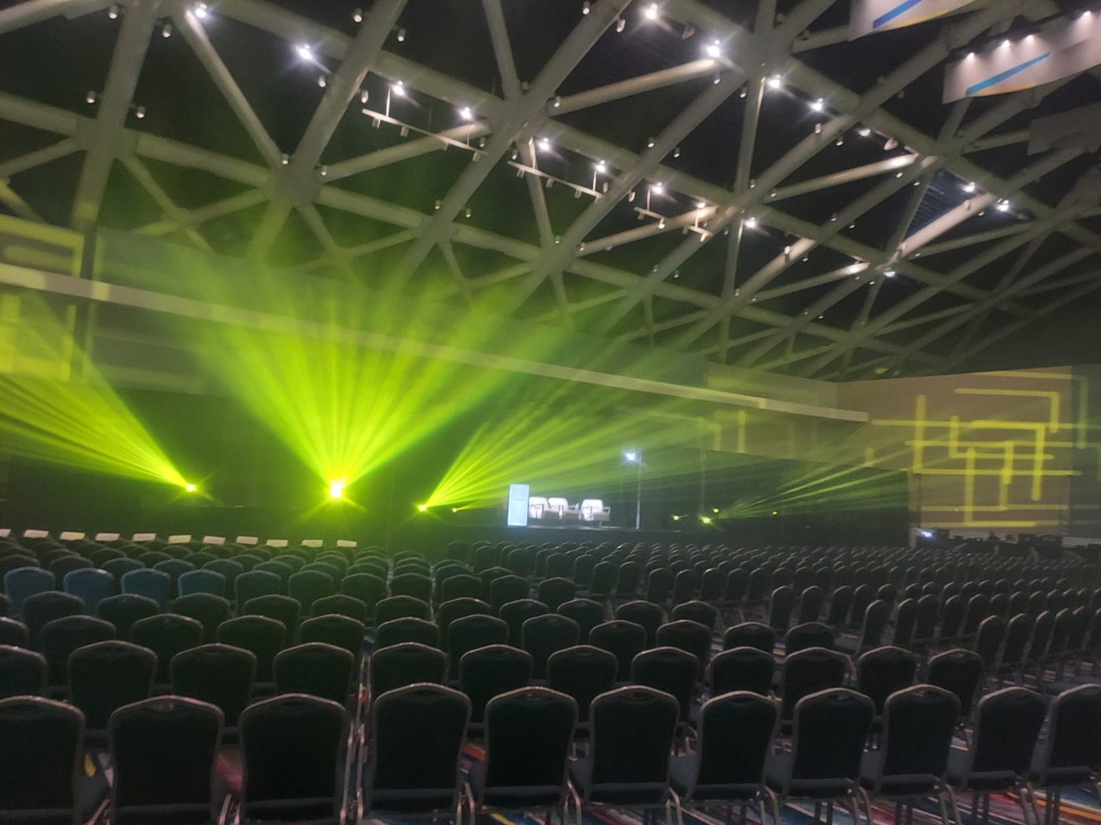 Yellow beams light up a conference hall above rows of seating